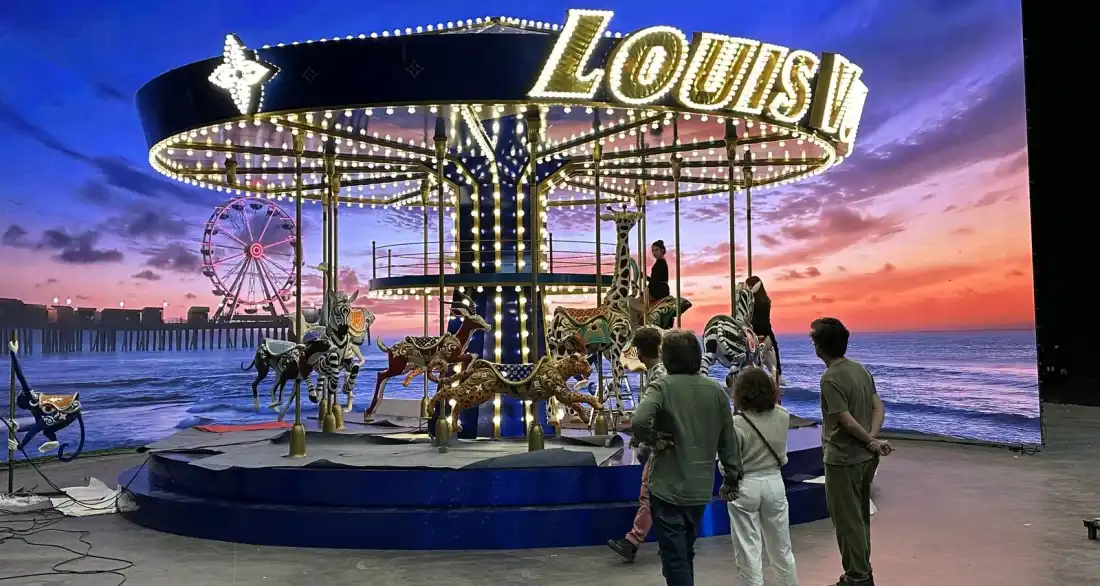 Въртележката на Louis Vuitton пред LED стена със залез над морето