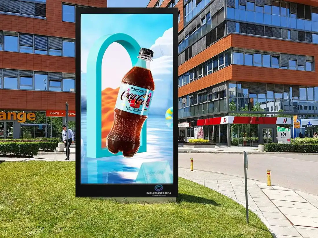 Outdoor LED totem at Business Park Sofia in direct sun, with office buildings behind it