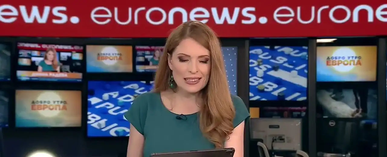 A presenter in the Euronews Bulgaria studio in front of the LED wall showing studio graphics